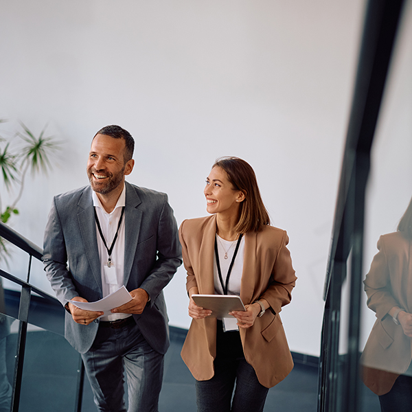 Happy,Businesswoman,And,Her,Coworker,Moving,Up,The,Stairs,In